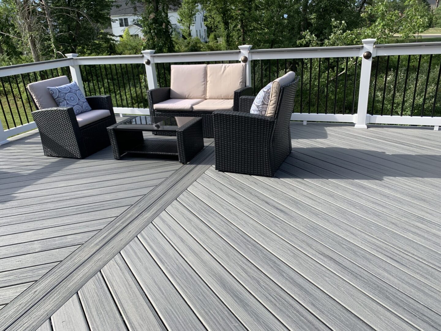 A deck with furniture and trees in the background.